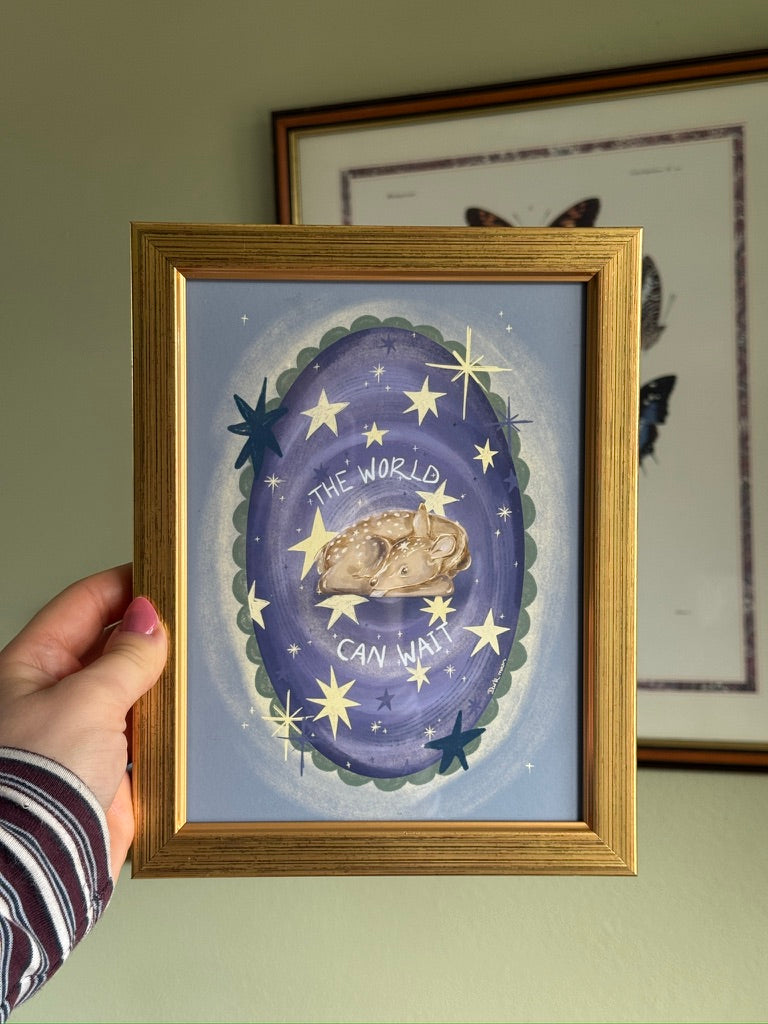 whimsical artwork with a purple background, stars and a deer, held by a hand.