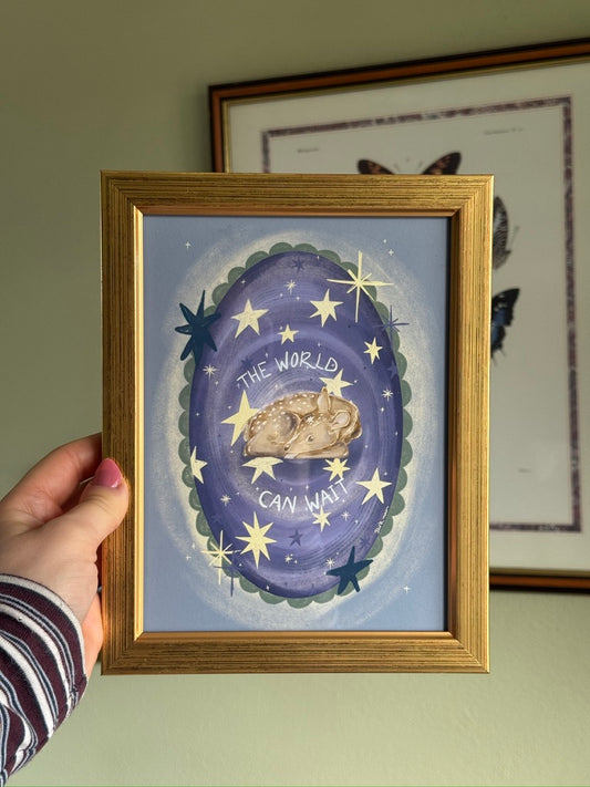 whimsical artwork with a purple background, stars and a deer, held by a hand.