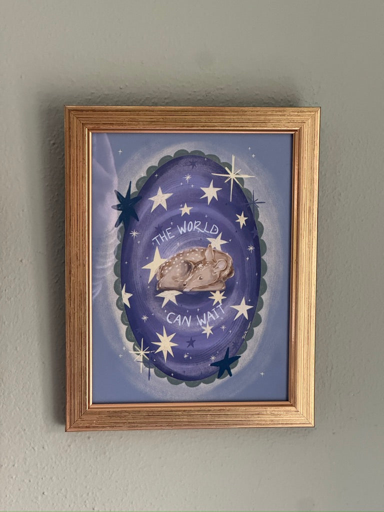 Framed artwork with a purple background, stars, and a deer, on a gray wall.