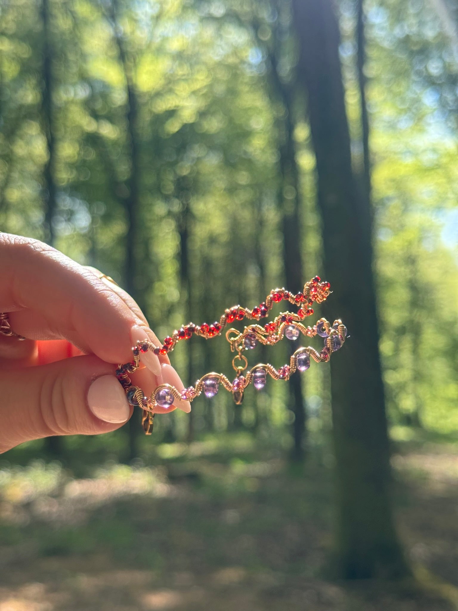 Hand holding a bracelet with a forest background