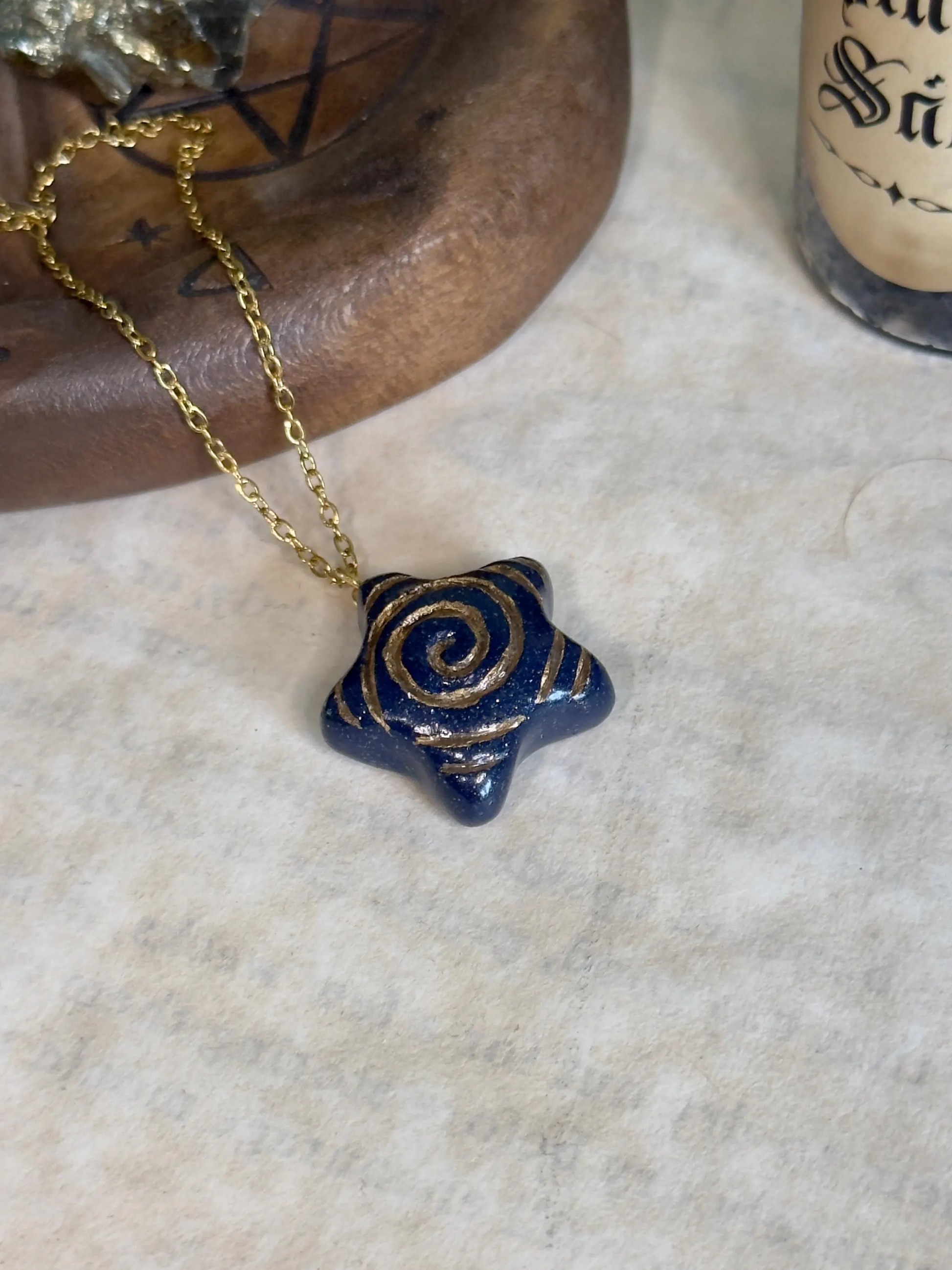 Blue star-shaped pendant with gold chain on a textured surface