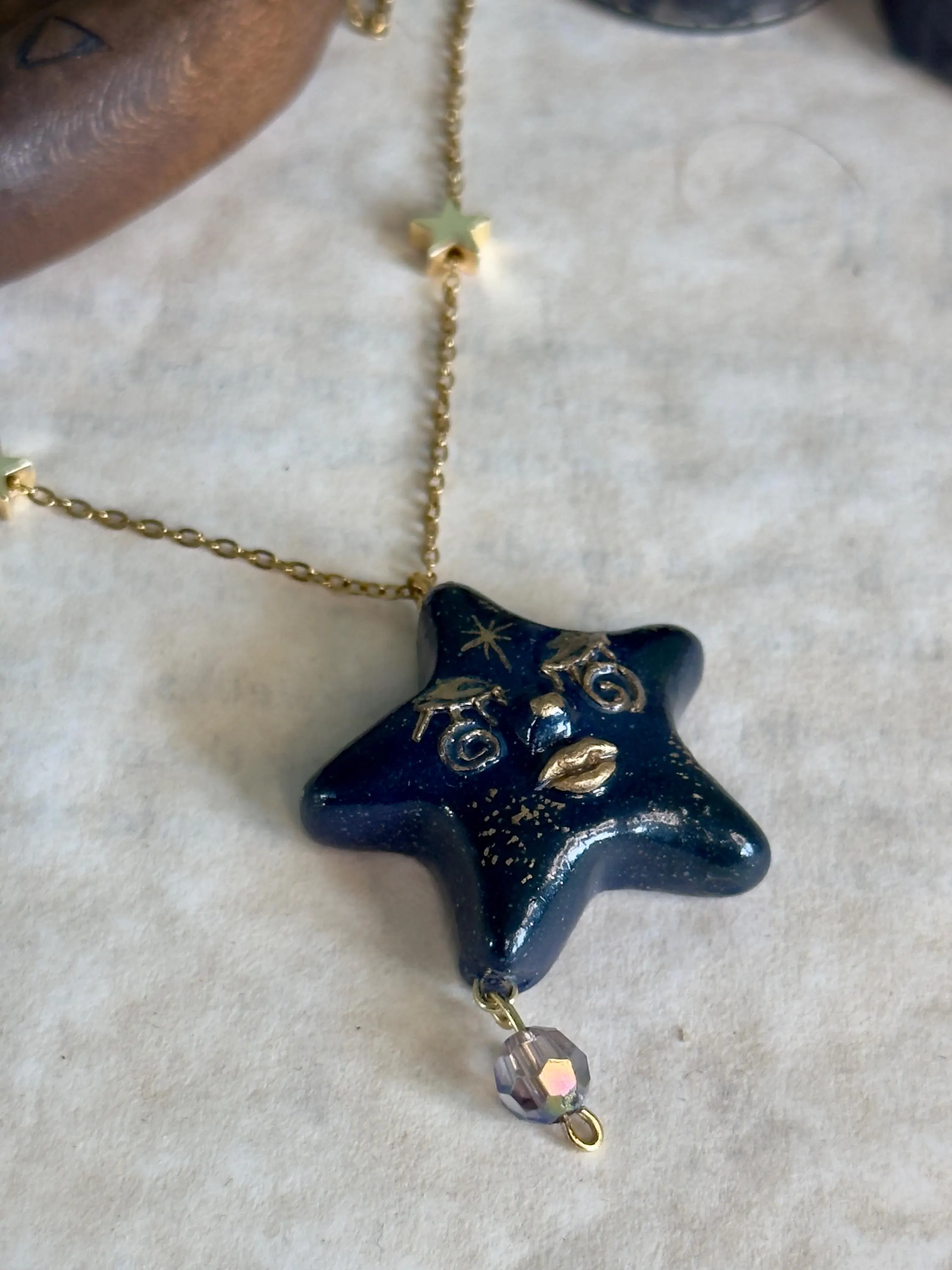 Blue Star-shaped pendant necklace with gold chain on a textured surface