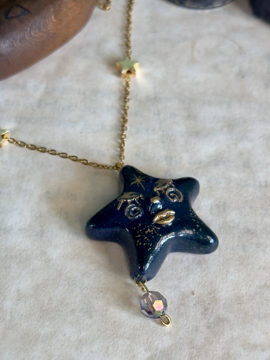 Blue Star-shaped pendant necklace with gold chain on a textured surface