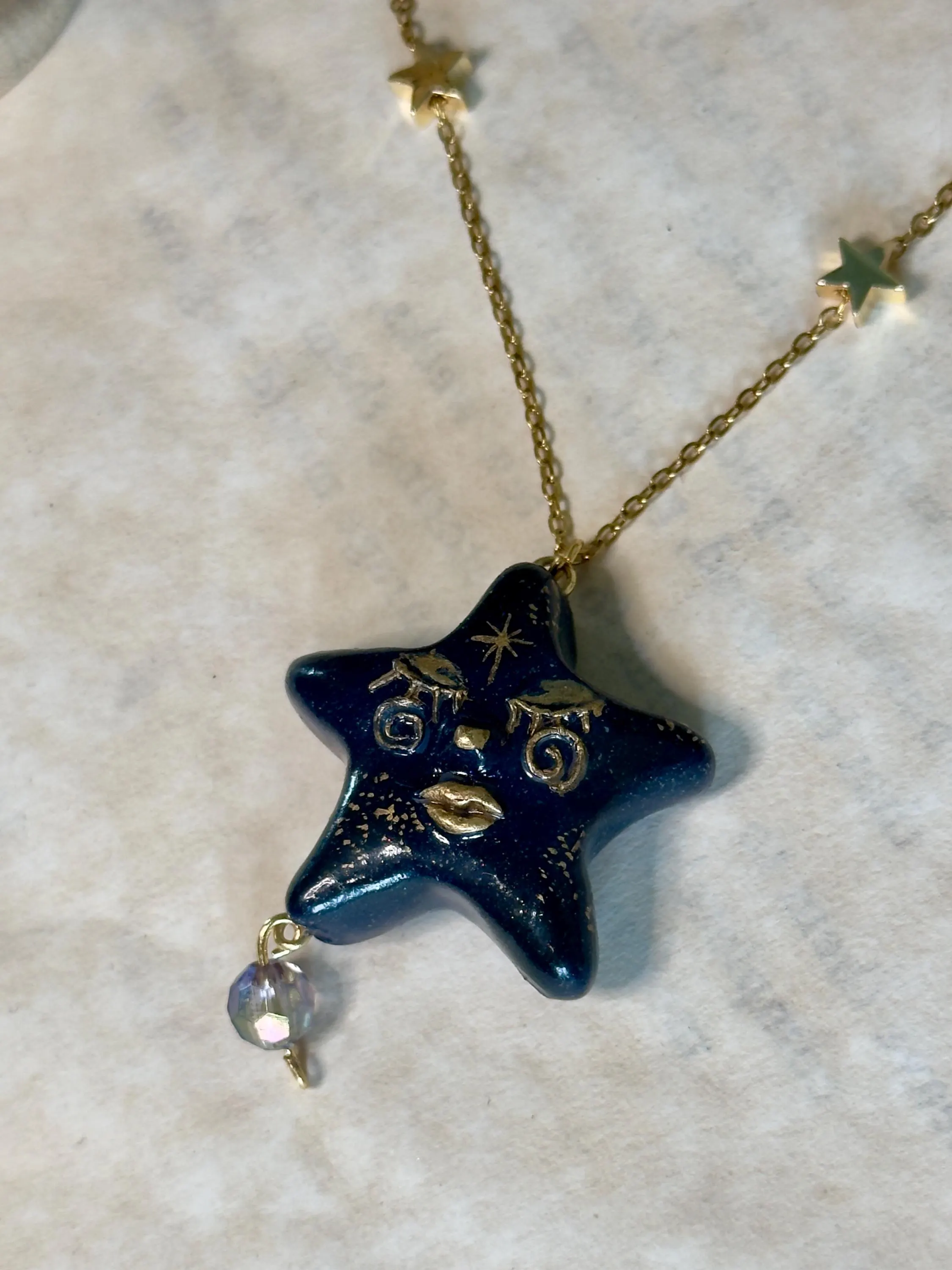 Blue Star-shaped pendant necklace with gold chain on a marble surface