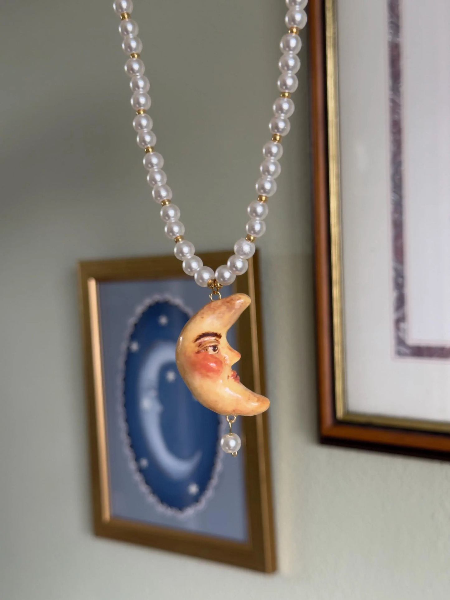 Pearl necklace with a crescent moon pendant against a neutral background